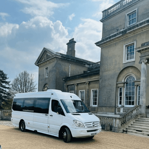 A Mercedes minibus parked in front of a grand mansion, showcasing elegance and luxury.